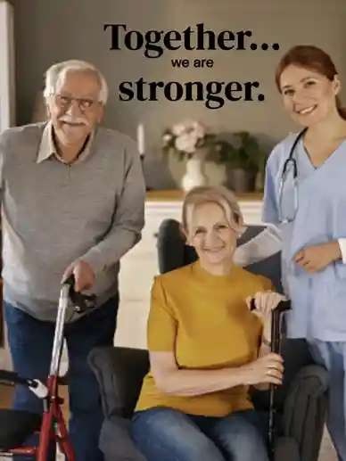 A senior man, woman in wheelchair, and female caregiver smiling together indoors.